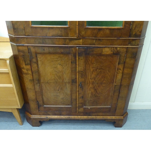 326 - An early 20thC Georgian design walnut corner cabinet with a pair of glazed doors, over a pair of pan... 