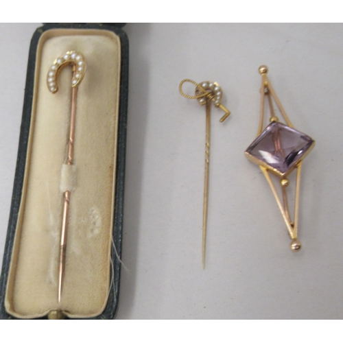 163 - Three 15ct gold stickpins, viz. one of geometric form, set with an amethyst coloured stone; and two ... 