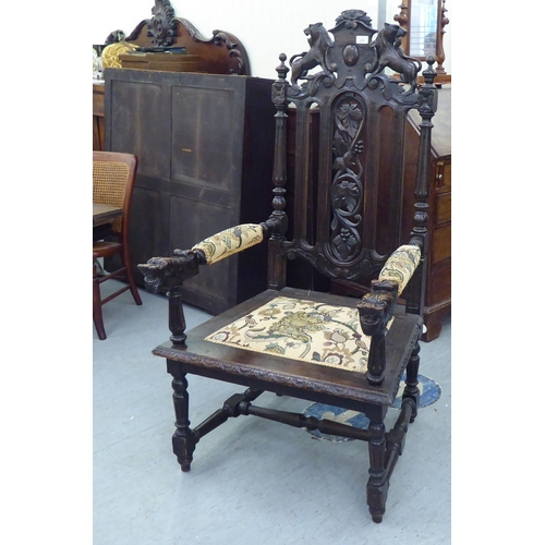 235 - A late 19th/early 20thC stained and carved oak throne chair with a decorative armorial crest and fru... 