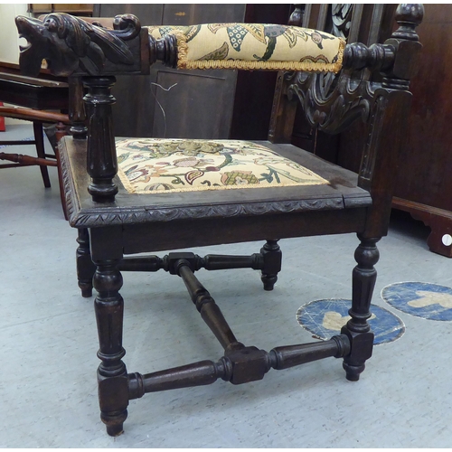 235 - A late 19th/early 20thC stained and carved oak throne chair with a decorative armorial crest and fru... 