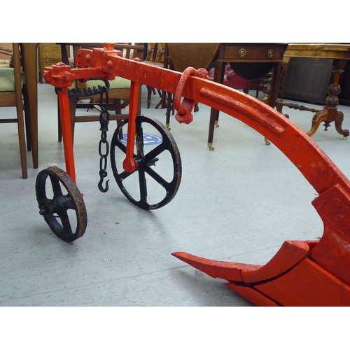 249 - An early 20thC Howard red painted steel horse drawn plough, on iron spoked wheels  120