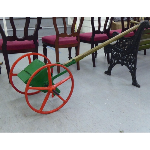 253 - An early 20thC red and green painted steel seed spreader, on a wooden handle  70