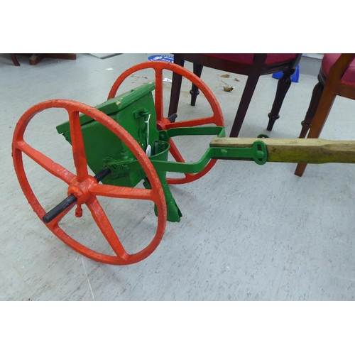 253 - An early 20thC red and green painted steel seed spreader, on a wooden handle  70