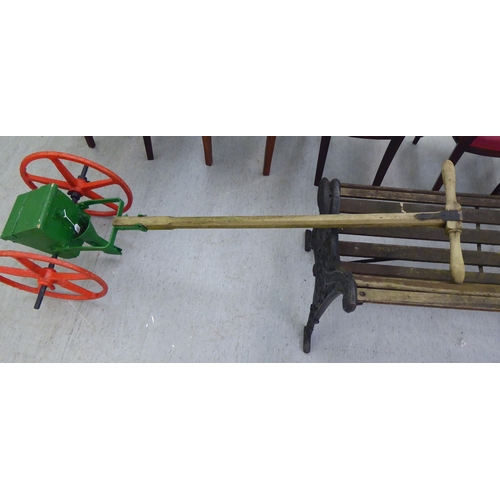 253 - An early 20thC red and green painted steel seed spreader, on a wooden handle  70