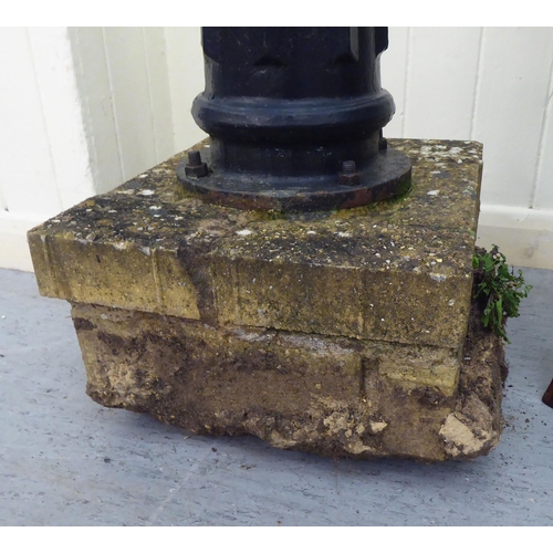 258 - A Terpo black painted cast iron water pump head, secured to a concrete plinth  65