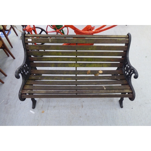 259 - A 20thC Victorian design garden bench seat with black painted cast iron ends and teak slats  50