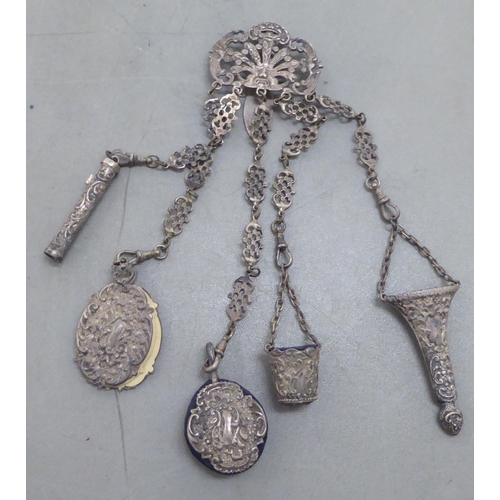 264 - A late 19th/early 20thC decoratively cast white metal chatelaine, comprising a belt hook and four pe... 