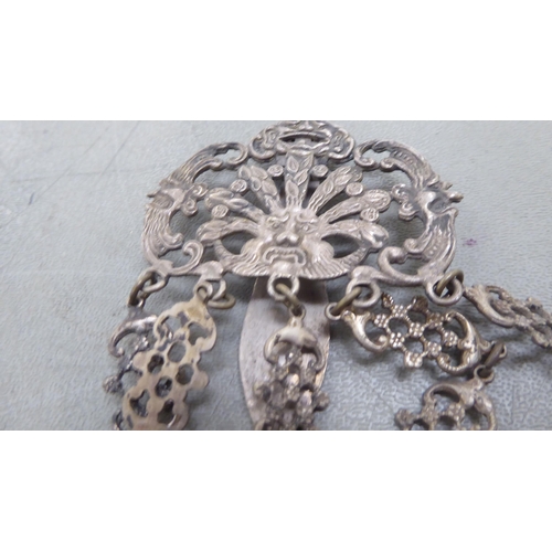 264 - A late 19th/early 20thC decoratively cast white metal chatelaine, comprising a belt hook and four pe... 