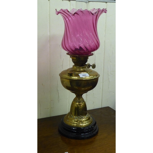 286 - A late Victorian brass oil lamp, the reservoir on an embossed cone shape pedestal and ceramic base  ... 