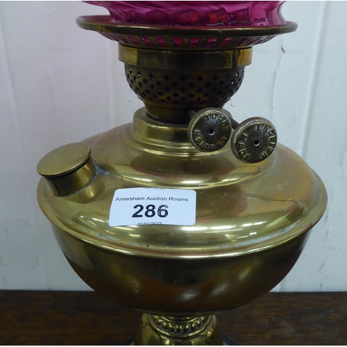 286 - A late Victorian brass oil lamp, the reservoir on an embossed cone shape pedestal and ceramic base  ... 