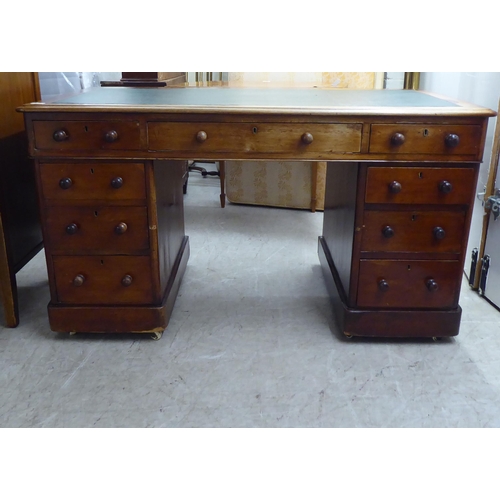 298 - A late Victorian mahogany nine drawer, twin pedestal desk with bun handles and a green fabric scribe... 