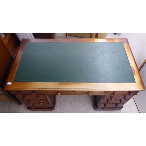 298 - A late Victorian mahogany nine drawer, twin pedestal desk with bun handles and a green fabric scribe... 