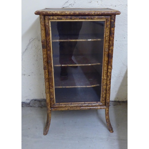 306 - A late 19th/early 20thC bamboo framed cabinet bookcase, enclosed by a full height, glazed panelled d... 