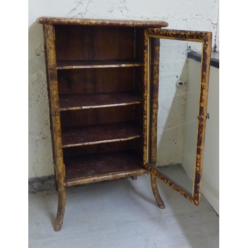 306 - A late 19th/early 20thC bamboo framed cabinet bookcase, enclosed by a full height, glazed panelled d... 