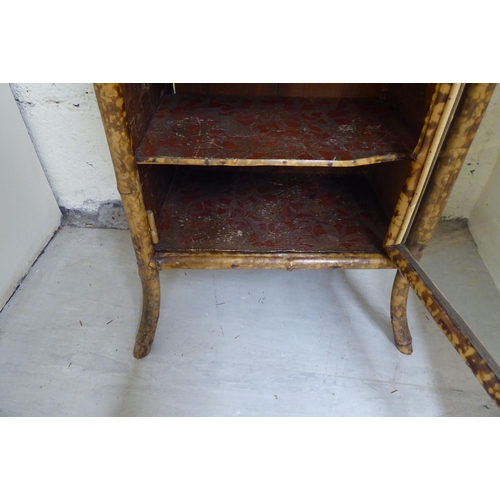 306 - A late 19th/early 20thC bamboo framed cabinet bookcase, enclosed by a full height, glazed panelled d... 