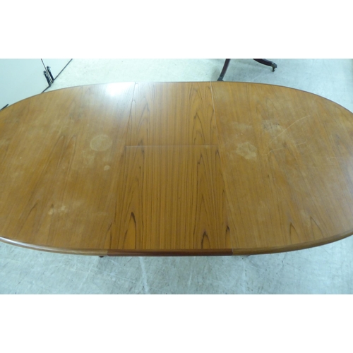 308 - A modern teak extending dining table, the oval top incorporating an integrated additional leaf, rais... 