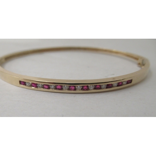 323 - A 9ct gold diamond and ruby bangle