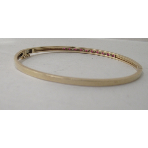 323 - A 9ct gold diamond and ruby bangle