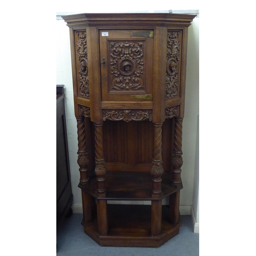 33 - A late 19th/early 20thC Continental light oak credence style cupboard with heavily carved ornament, ... 