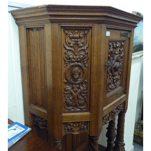 33 - A late 19th/early 20thC Continental light oak credence style cupboard with heavily carved ornament, ... 