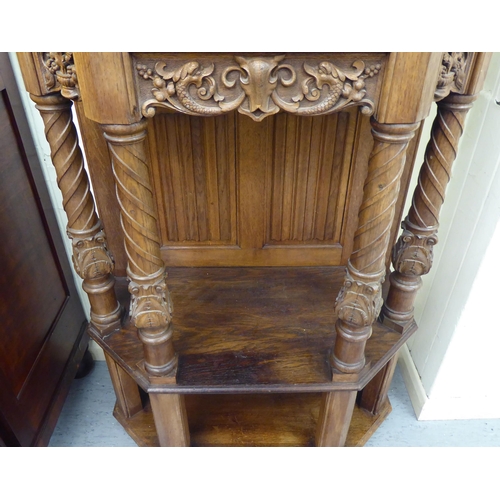 33 - A late 19th/early 20thC Continental light oak credence style cupboard with heavily carved ornament, ... 