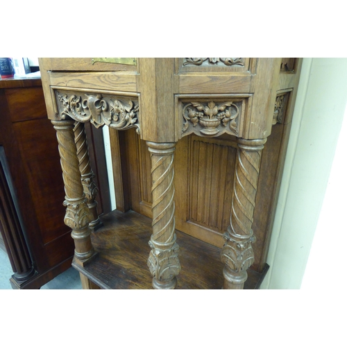 33 - A late 19th/early 20thC Continental light oak credence style cupboard with heavily carved ornament, ... 