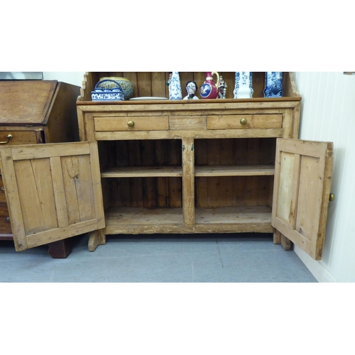 59 - A 20thC reconstituted pine, one piece dresser with three open shelves, over two drawers and two door... 