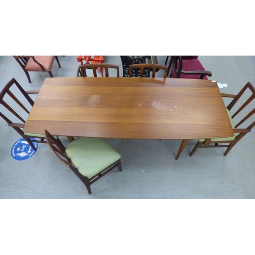 296 - A 1970s/1980s teak dining table, the one piece top with sides, raised on turned, tapered legs  29.5