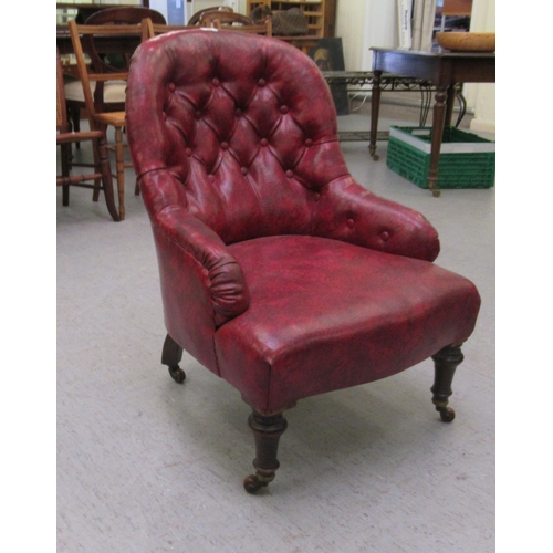 108 - An early 20thC nursing chair, part button upholstered in ox blood coloured hide, raised on turned le... 