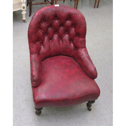 108 - An early 20thC nursing chair, part button upholstered in ox blood coloured hide, raised on turned le... 