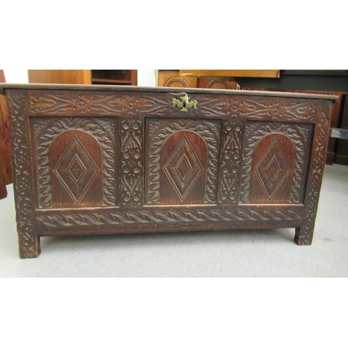 109 - A late 18th/early 19thC carved oak panelled coffer with straight sides and a hinged lid, raised on b... 