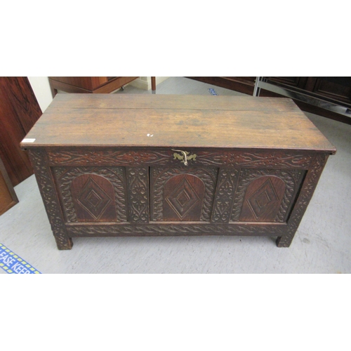 109 - A late 18th/early 19thC carved oak panelled coffer with straight sides and a hinged lid, raised on b... 