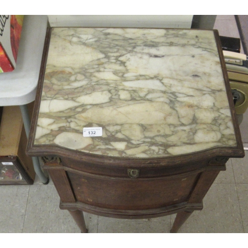 132 - A late 19thC walnut and marquetry bedside cabinet with a marble top, over a drawer and a door, raise... 