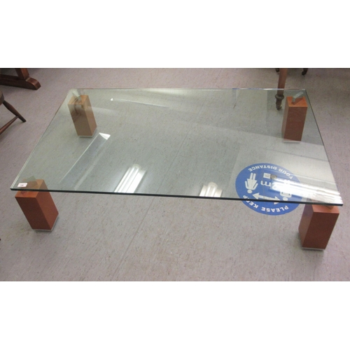 196 - A modern coffee table with a clear plate glass top, raised on substantial square mahogany finished l... 