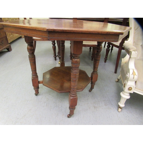 217 - An early 20thC mahogany octagonal occasional table, raised on ring turned legs and casters, united b... 