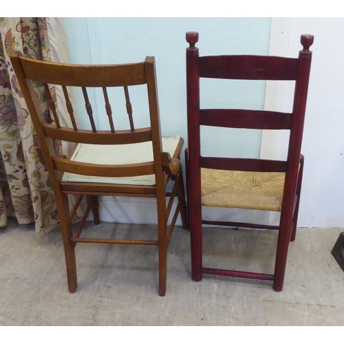 23 - A late 19thC stained beech framed, ladder back chair with a rush seat; and a later beech framed side... 