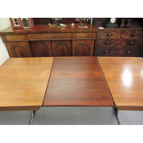 275 - In the manner of Heals, a 1970s rosewood veneered draw action dining table, raised on a cast metal a... 