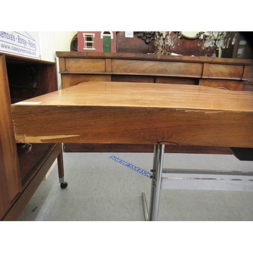 275 - In the manner of Heals, a 1970s rosewood veneered draw action dining table, raised on a cast metal a... 