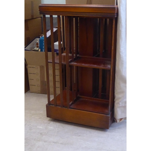 291 - A reproduction of an Edwardian string inlaid yewwood, two tier revolving bookcase, on a plinth and c... 