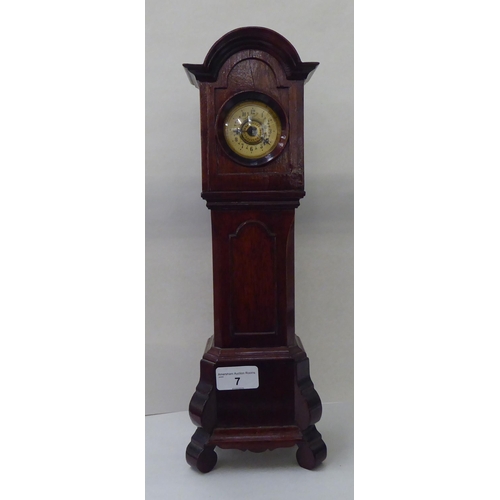 7 - An early 20thC mahogany mantel timepiece, fashioned as a longcase clock with an arched hood and stra... 