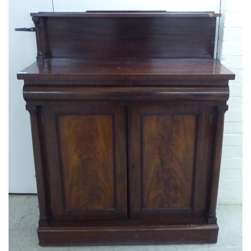 93 - A mid Victorian mahogany chiffonier with an open upstand, over a frieze and a pair of panelled doors... 