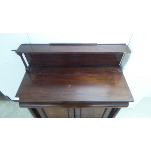 93 - A mid Victorian mahogany chiffonier with an open upstand, over a frieze and a pair of panelled doors... 