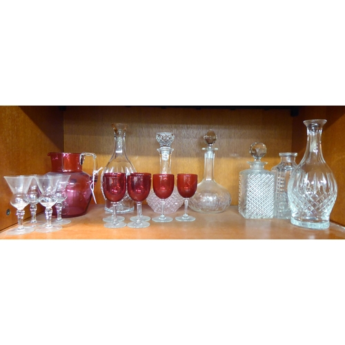 12 - Glassware: to include a clear and cranberry coloured cordial jug and six decanters