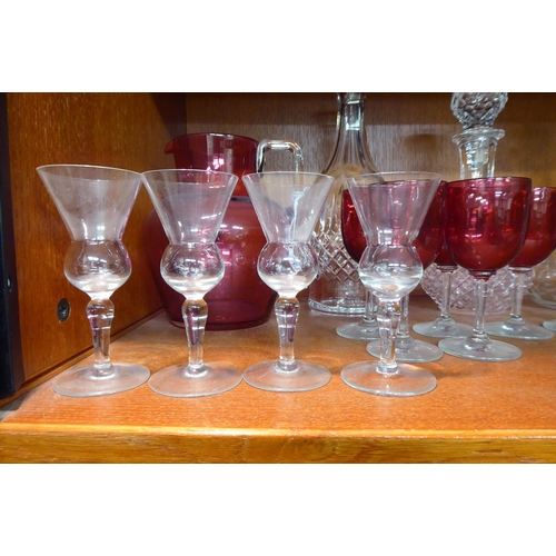 12 - Glassware: to include a clear and cranberry coloured cordial jug and six decanters