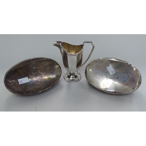 132 - A pair of silver backed hairbrushes; and a silver helmet shaped, octagonal, pedestal cream jug ... 