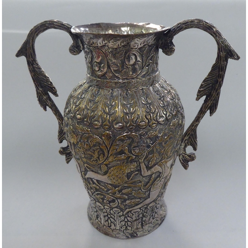 136 - An Indian white metal on copper twin handled vase, profusely decorated with figures, animals and fol... 