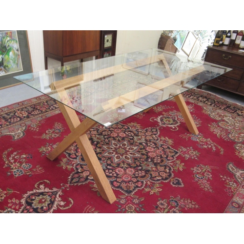 18 - A modern dining table, the glass top set on a light oak, crossover frame  28.5