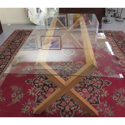 18 - A modern dining table, the glass top set on a light oak, crossover frame  28.5