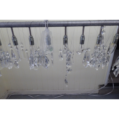 222 - A modern pendant light fitting, comprising eleven inline bulb holders, on a stainless steel bar with... 