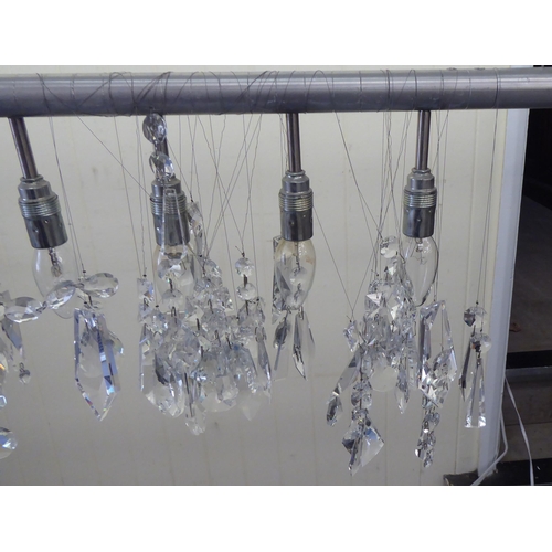 222 - A modern pendant light fitting, comprising eleven inline bulb holders, on a stainless steel bar with... 